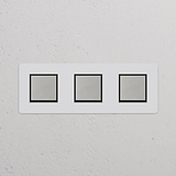 Trois Interrupteur VV Carré x3 (Plaque Triple) avec un Insert Nickel Poli Peignable Noir sur un mur blanc.