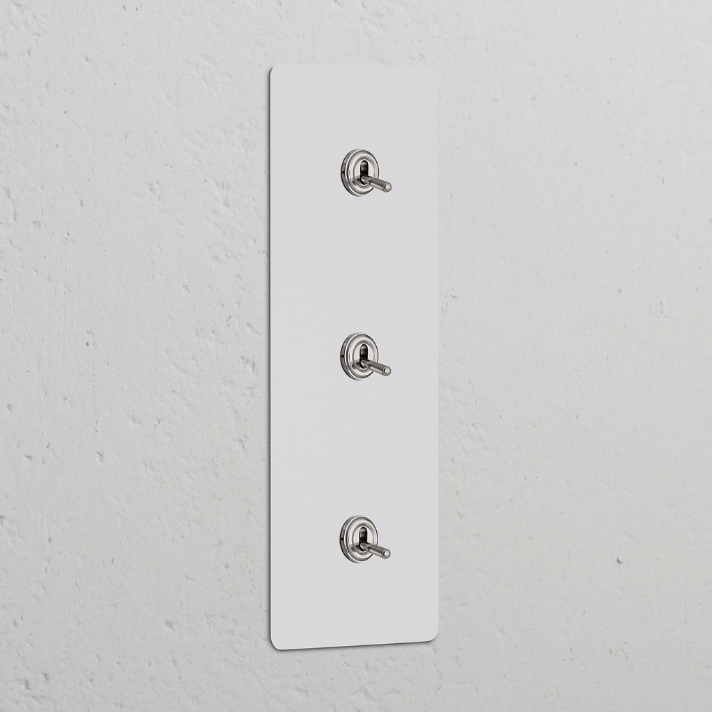 Interrupteur VV avec trois leviers verticaux sur plaque triple, finition nickel poli peignable.