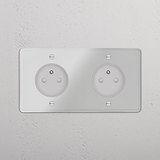 Douilles rondes doubles de type E sur plaque double avec finition transparente et insert blanc, montées sur un mur texturé.