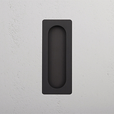 Poignée de porte rectangulaire en bronze encastrée dans un mur gris clair, Regent Moyenne Poignée Encastrée Porte Galandage.