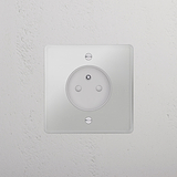 Prise ronde transparente Type E (Plaque Simple) avec insert blanc montée sur un mur texturé.