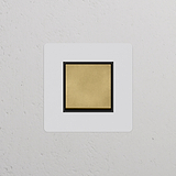 Interrupteur VV Carré, plaque simple en laiton ancien avec insert noir, sur fond de mur texturé blanc.