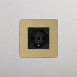 Presa Modulo Singolo Schuko/Bipasso con finitura in ottone nero anticato su telaio beige, montata su parete grigia.