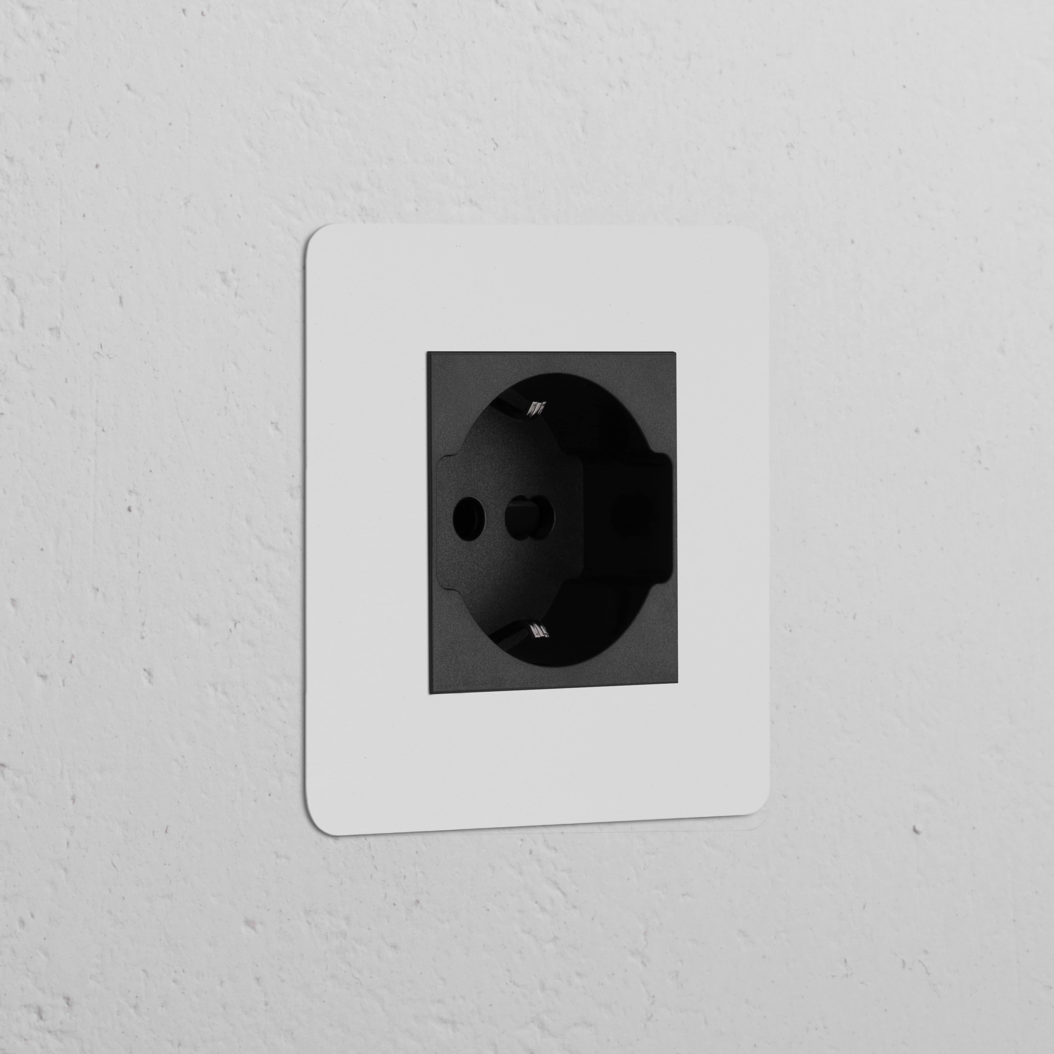 Modulo spina Schuko/Bipasso Nero Verniciabile Nero su parete bianca testurizzata, per prese elettriche singole.