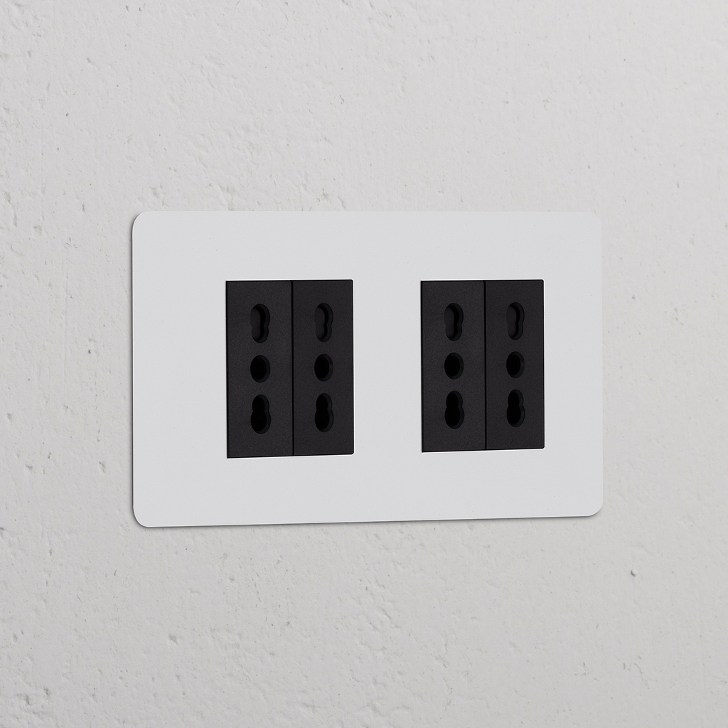 Prese doppie nere, Modulo di alimentazione Bipasso 4x Doppio, su parete bianca per collegamenti elettrici versatili.