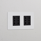 Prese doppie nere, Modulo di alimentazione Bipasso 4x Doppio, su parete bianca per collegamenti elettrici versatili.