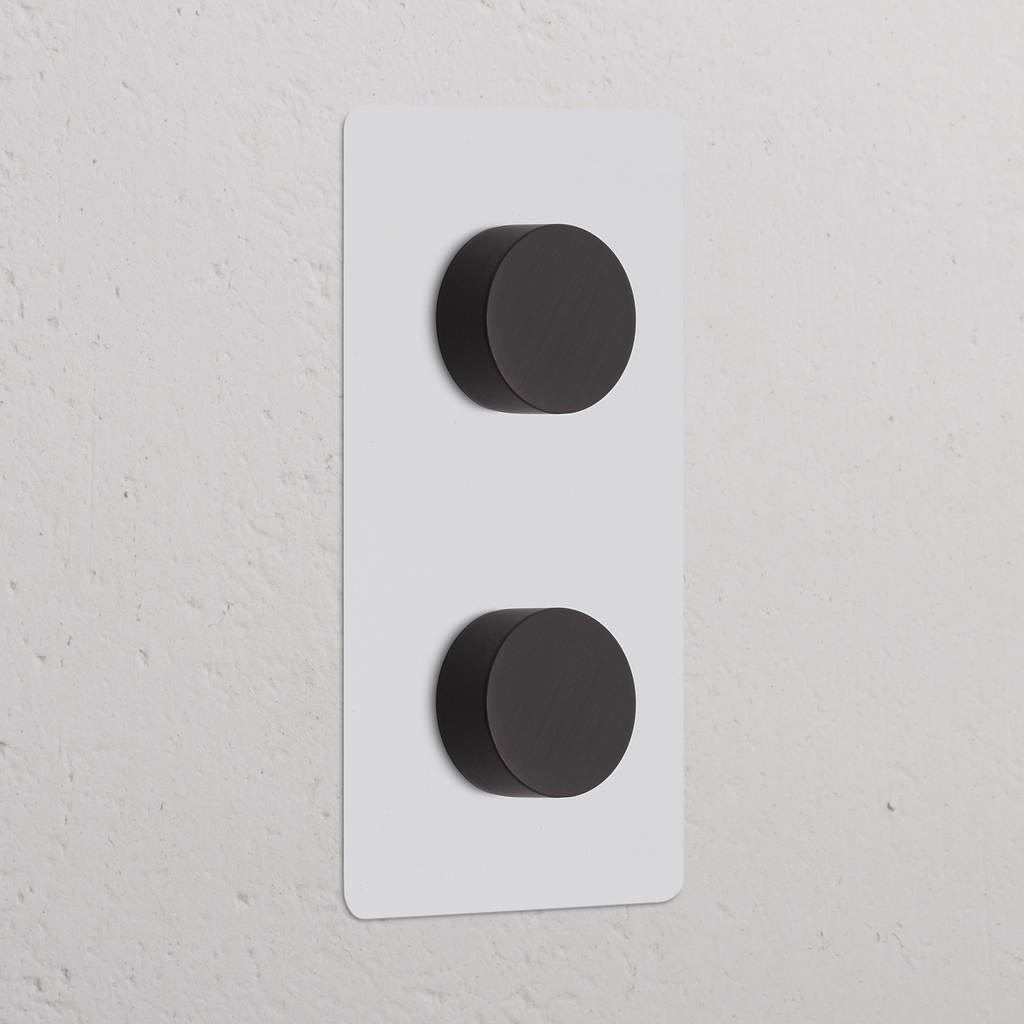 Due interruttori dimmer verticali in bronzo, 'Interruttore Dimmer Doppio Verticale 2x', su un pannello a parete bianco.