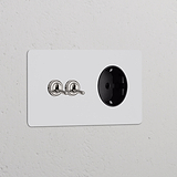 Doppio interruttore a levetta 2x in nichel nero con modulo di alimentazione Schuko Tipo F su piastra a muro verniciabile.