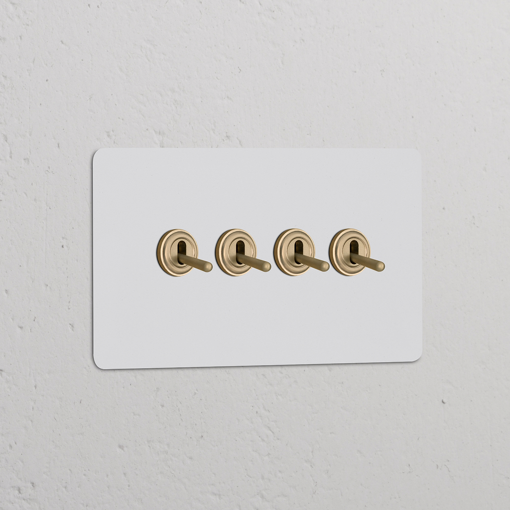 Interruptor articulado de quatro vias duplo em latão antigo pintável montado em painel branco na parede.