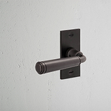 Digby Short Plate Sprung Door Handle Bronze Finish on White Background at an Angle