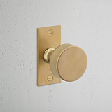 Onslow Short Plate Sprung Door Knob Antique Brass Finish on White Background at an Angle
