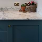 Antique brass Barlow Furniture Knob on a marble countertop, suitable for enhancing cabinets or drawers.