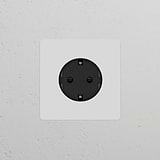 Black Schuko Type F single power module, paintable and round, perfect for seamless integration into wall designs.