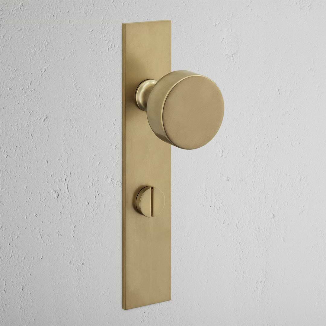 Onslow Long Plate Sprung Door Knob & Thumbturn Antique Brass Finish on White Background