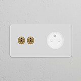 White double 2x toggle switch and French/Belgian Type E power module on antique brass plate against a textured wall.
