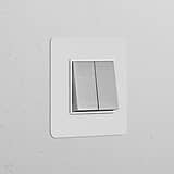 Paintable polished nickel white single 2x rocker switch on a textured white wall.