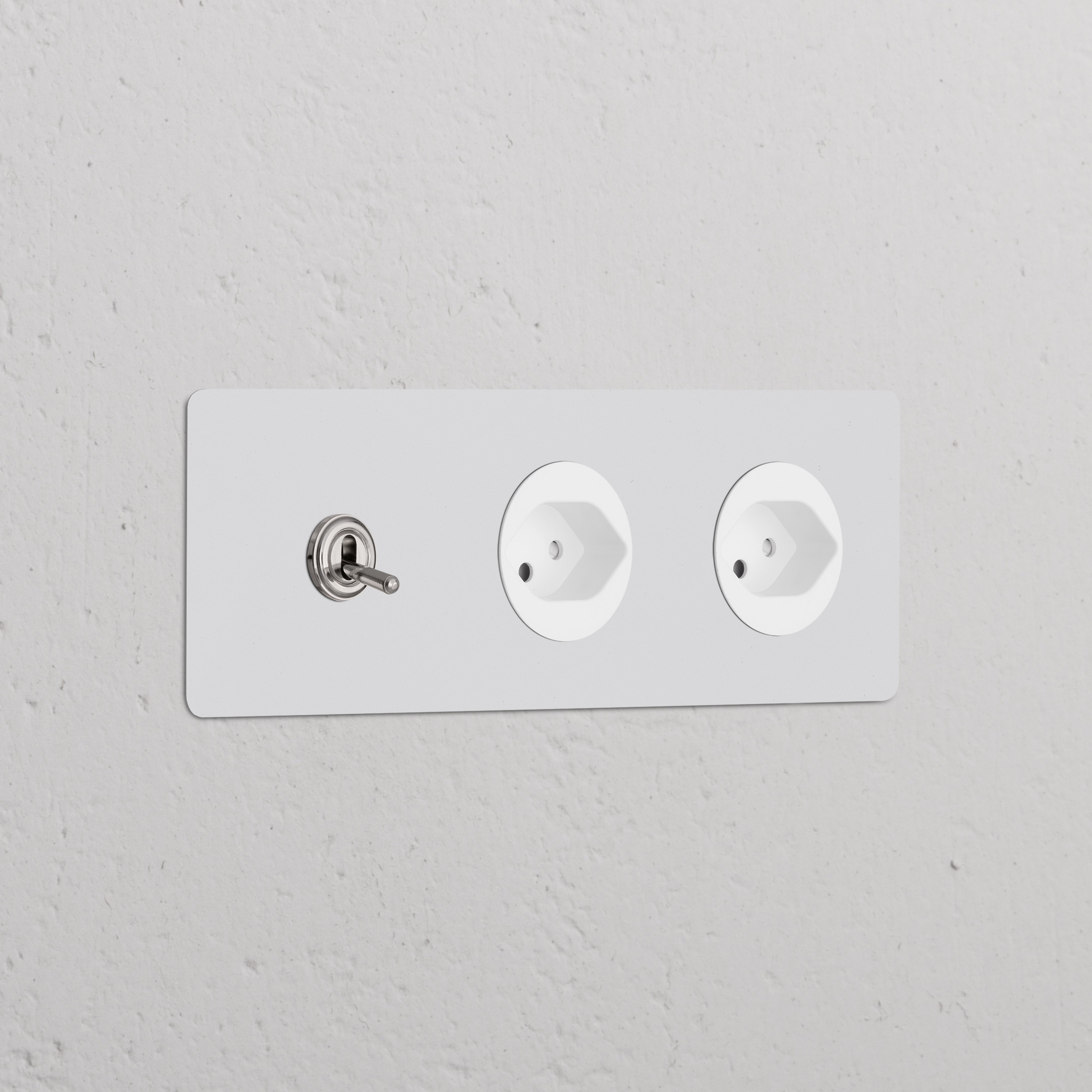 Triple Toggle Switch + 2x Swiss Type J Power Module in Paintable Polished Nickel on a white wall.