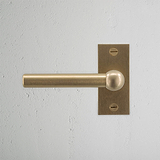 Harper Short Plate Sprung Door Handle Antique Brass Finish on White Background right Facing Front View