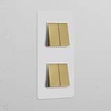 Paintable antique brass double vertical rocker switch blends with white textured wall, offering elegance and function.