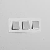 Triple 3x Rocker Switch in Paintable Polished Nickel White on a textured wall, adding functional elegance.
