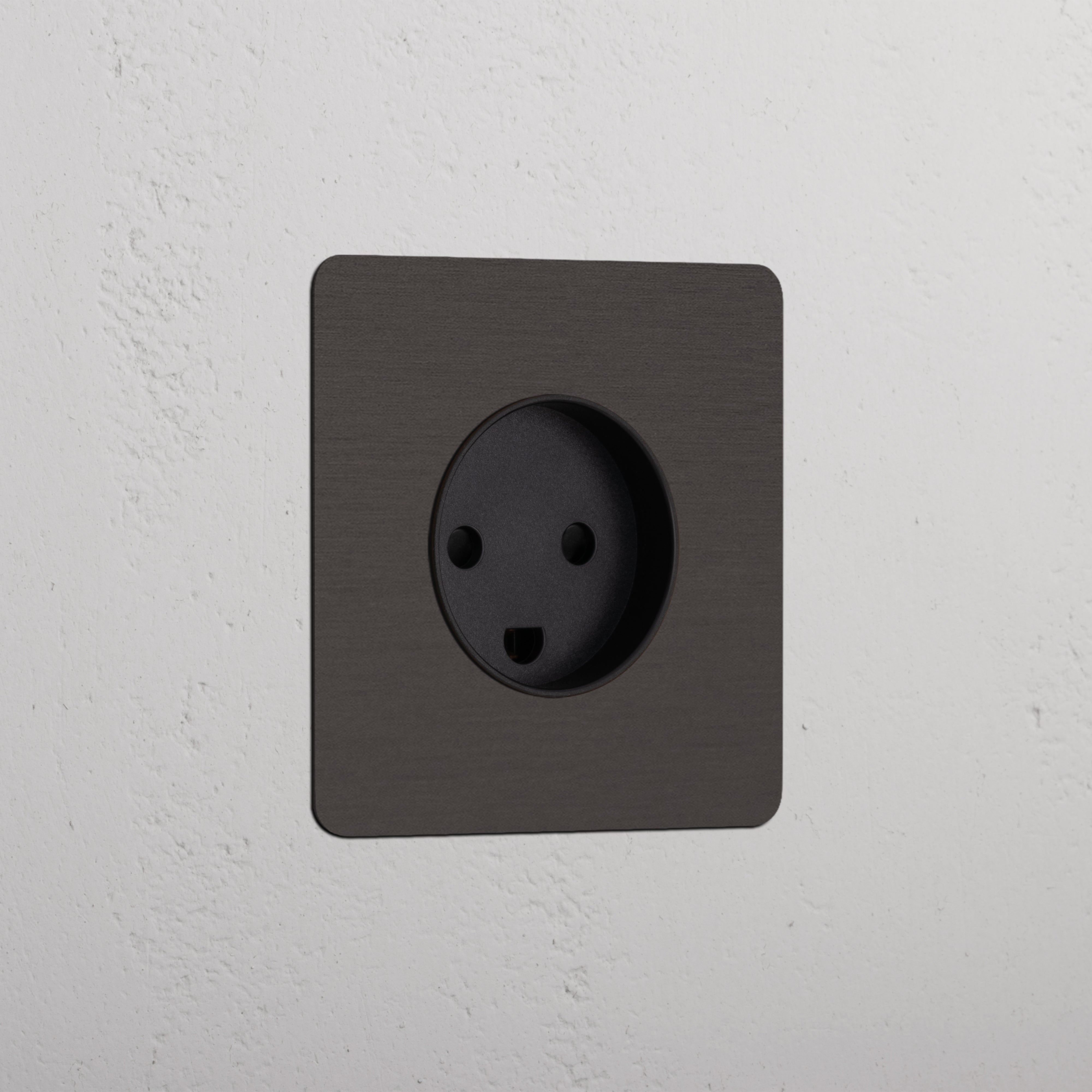 Bronze Black Single Danish Module socket on a white textured wall, designed for a sleek electrical outlet finish.