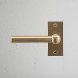 Harper Short Plate Sprung Door Handle Antique Brass Finish on White Background right Facing Front View