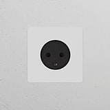 Single Danish Type K power module round, paintable black, mounted on a wall; single socket & module design.