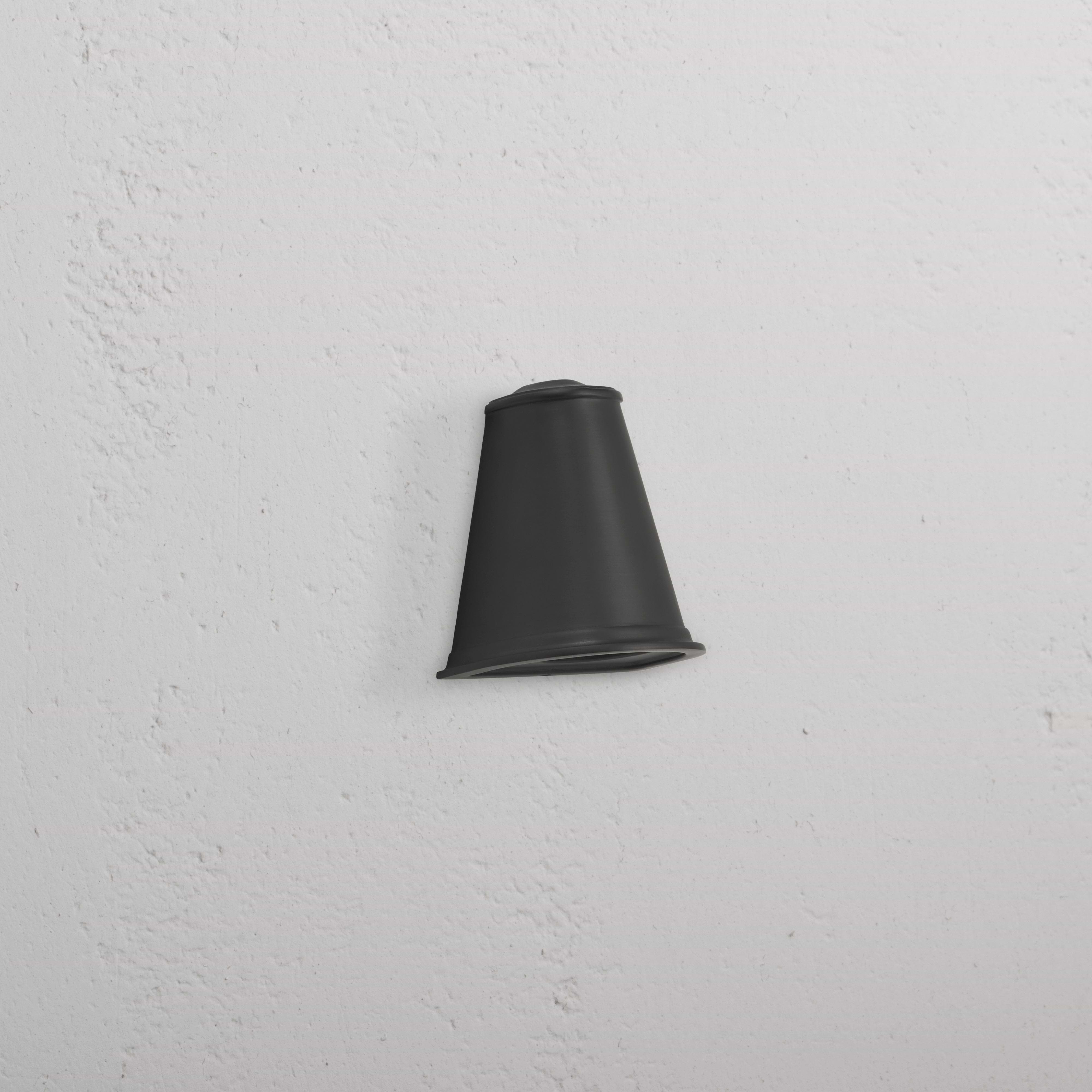 Southwark Mast Light – Bronze, a small bronze wall light with a rounded design, mounted on a white textured wall.