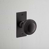 Poplar Short Plate Sprung Door Knob Bronze Finish on White Background at an Angle
