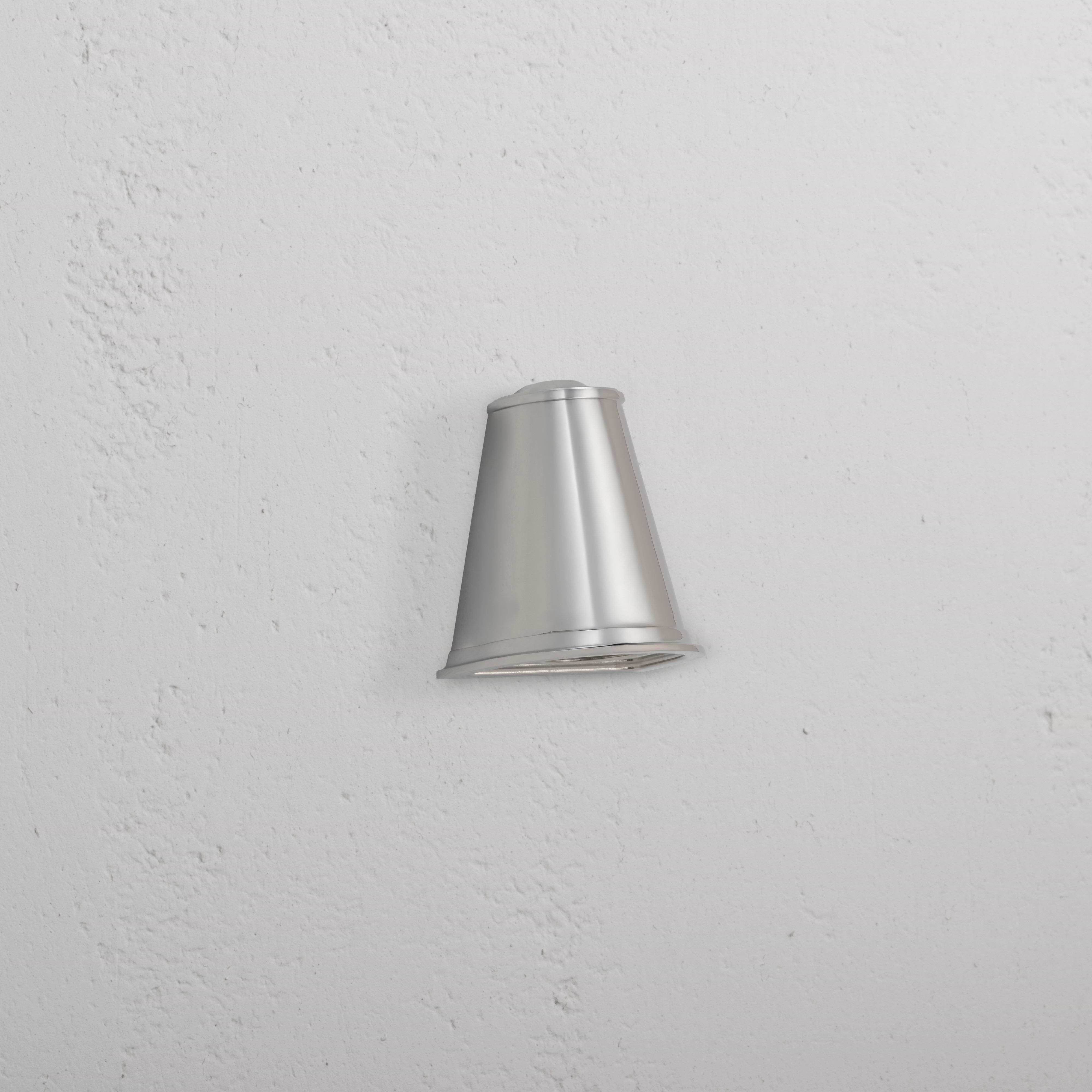 Southwark Mast Light – Polished Nickel, a small wall light with a sleek, conical design mounted on a white wall.