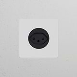Black Single Swiss Type J Power Module Round on a white wall; designed for single socket use and is paintable.