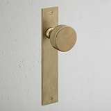 Onslow Long Plate Sprung Door Knob Antique Brass Finish on White Background at an Angle