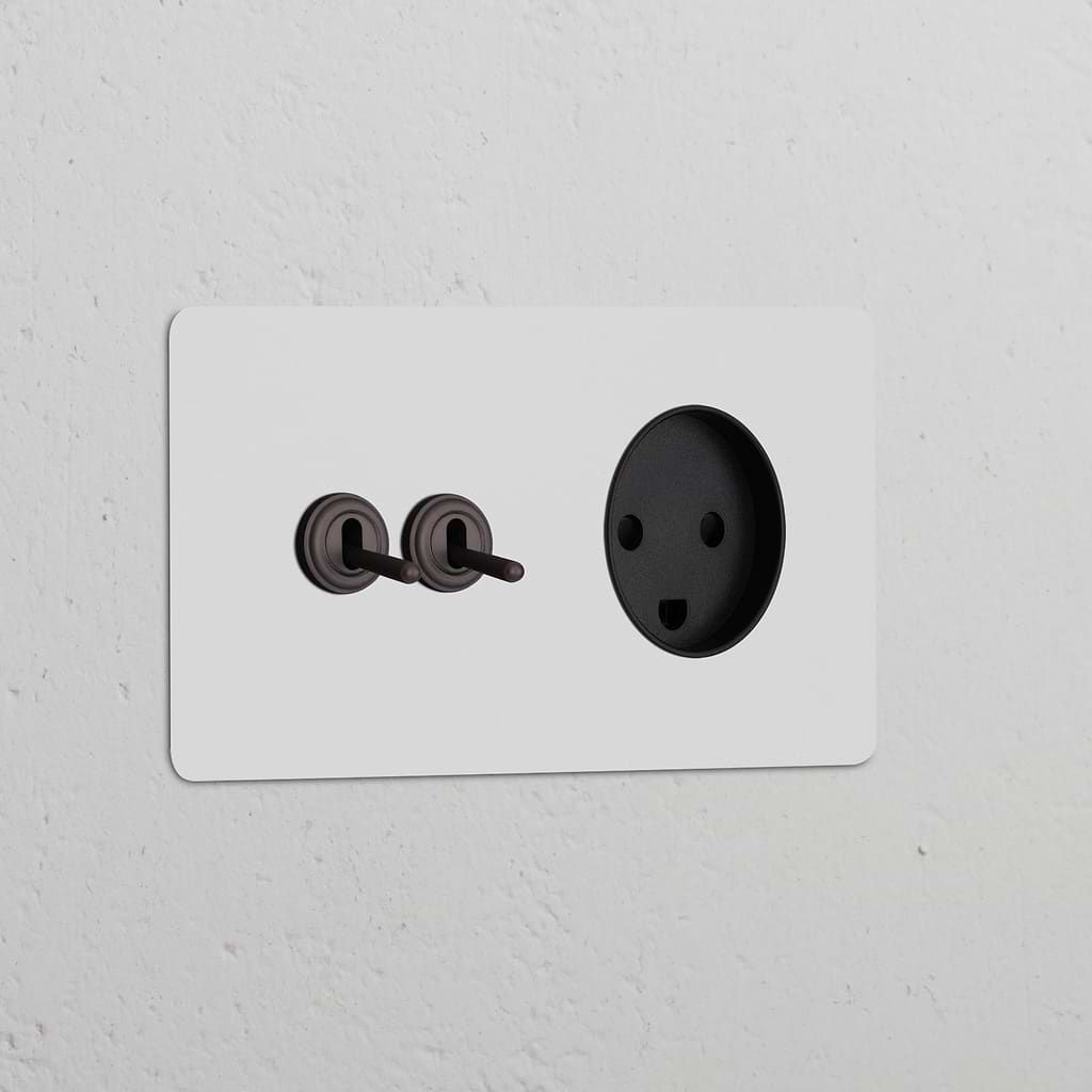 Double 2x toggle switch and Danish Type K power module in paintable bronze black finish against white textured wall.