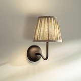 Medium Malvern Wall Light in Natural Beige at an angle affixed to a wall and turned on 