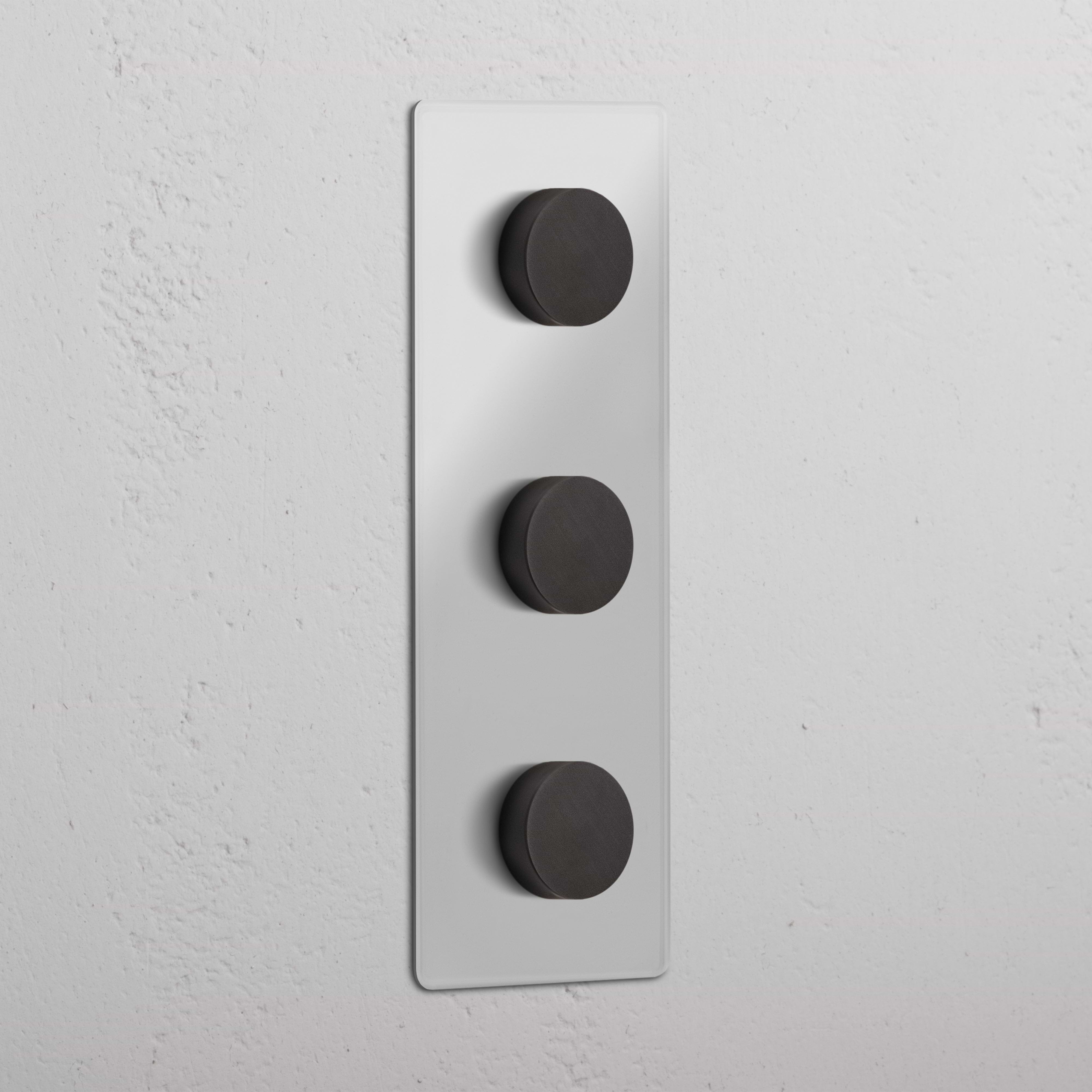 Triple 3x Vertical Multiway Dimmer Switch in Clear Bronze with three black knobs, mounted on a white wall.