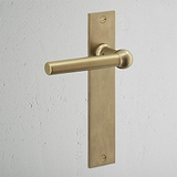 Harper Long Plate Sprung Door Handle Antique Brass Finish on White Background at an Angle