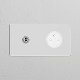 Double toggle switch and French/Belgian Type E power module in polished nickel white on a gray wall.