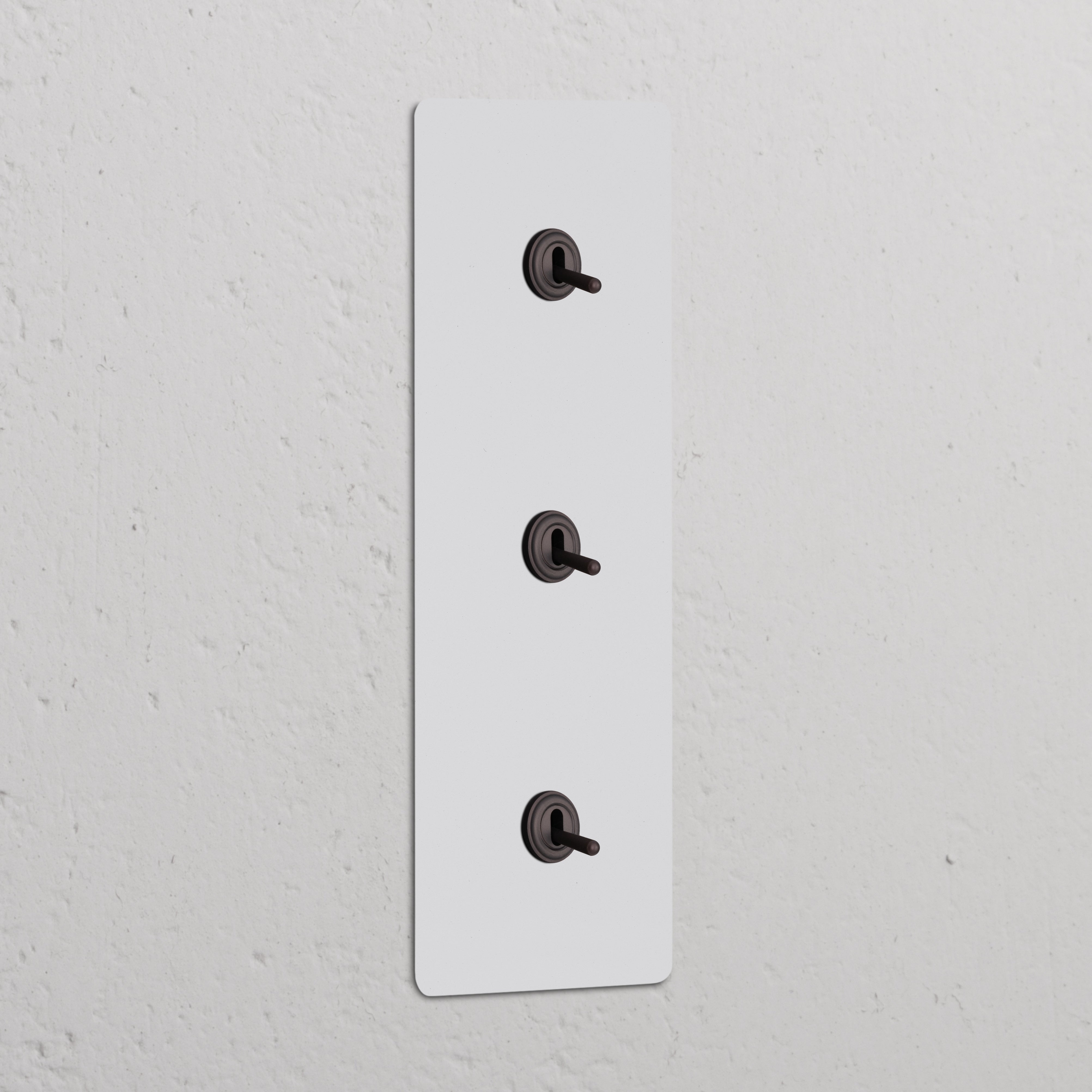 Triple 3x Vertical Toggle Switch in paintable bronze on a textured white wall.