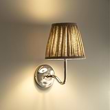 Small Malvern Wall Light in Natural Beige at an angle affixed to a wall and turned on 