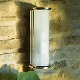 Bank Wall Light Fluted Glass – Polished Nickel, medium wall light with ribbed white glass shade on stone wall.