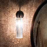 Bronze Claremount Small Wall Light Fluted glass fitted to a floral wallpapered wall with bathroom unit offset to the right. 