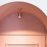 Antique brass Perryn Small Single Spotlight (35mm) casting warm light, ideal for highlighting specific areas.