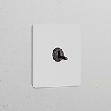 Single Toggle Switch in Paintable Bronze finish, part of the Single Switches & Dimmers collection, on a white wall.
