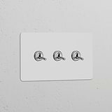 Polished nickel triple toggle switch on a paintable white panel, part of Double Switches & Dimmers collection.