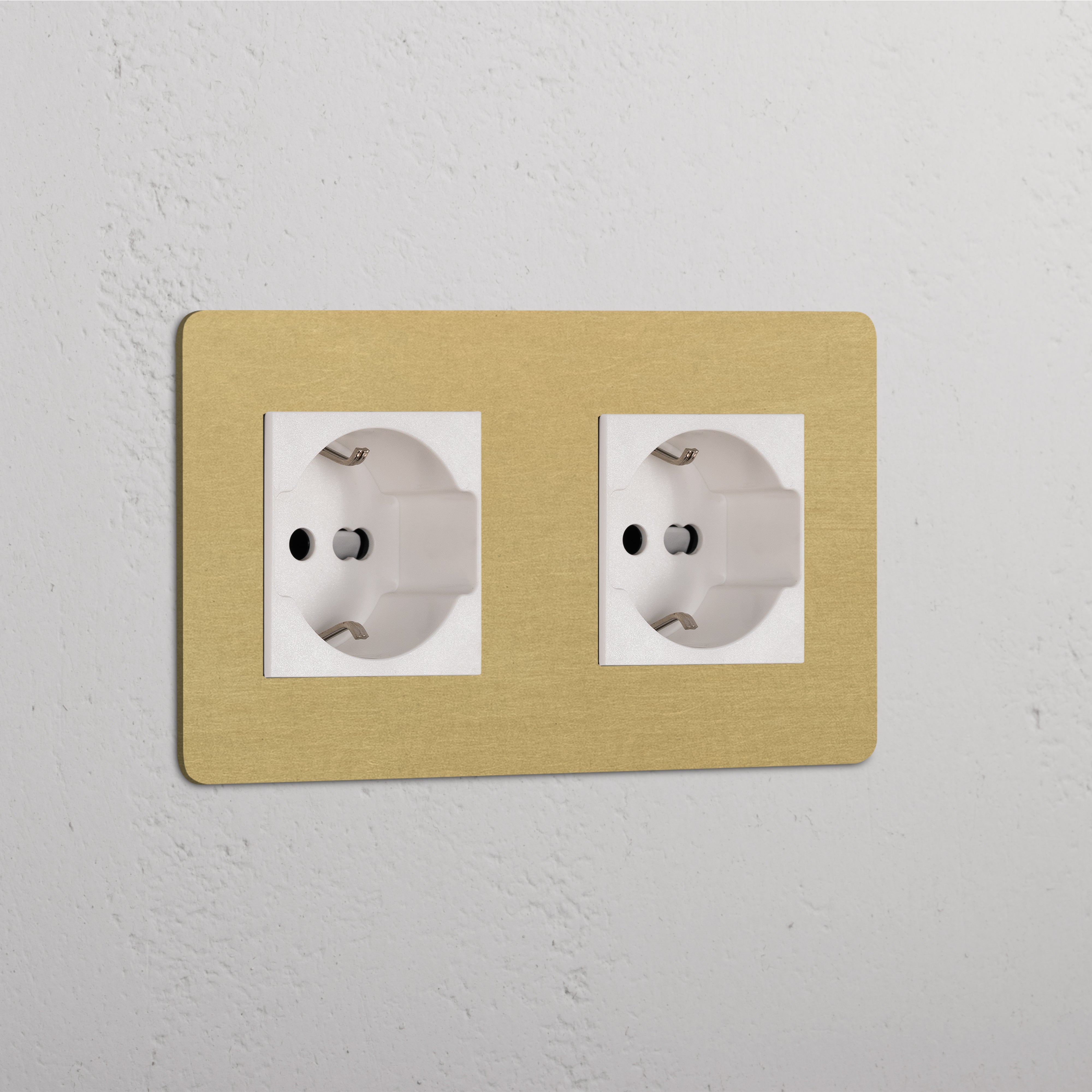 Double 2x Schuko/Bipasso Module in Antique Brass White on a textured white wall with two sockets.