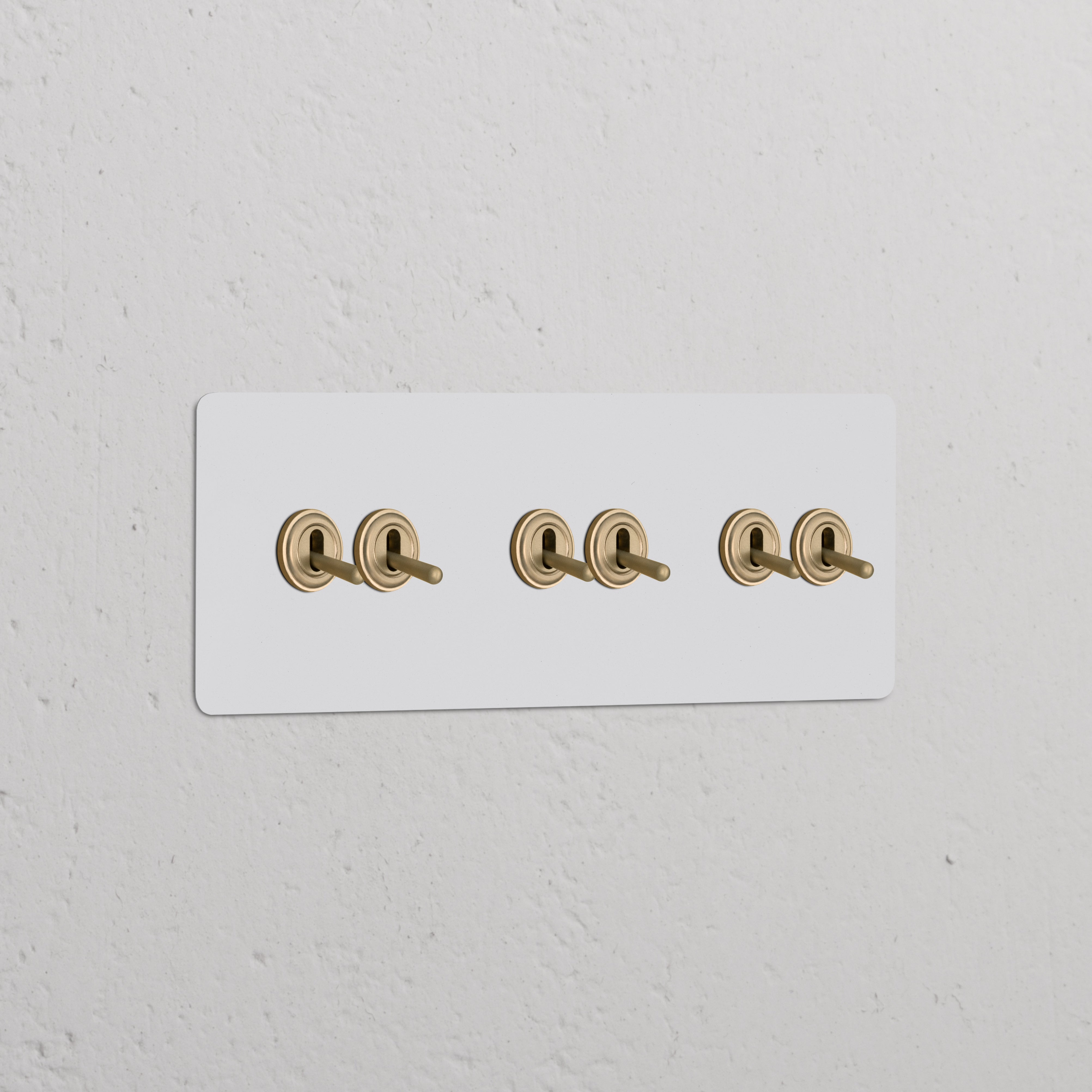 Triple 6x Toggle Switch Paintable Antique Brass on white plate, mounted on textured wall. Ideal for switches & dimmers.