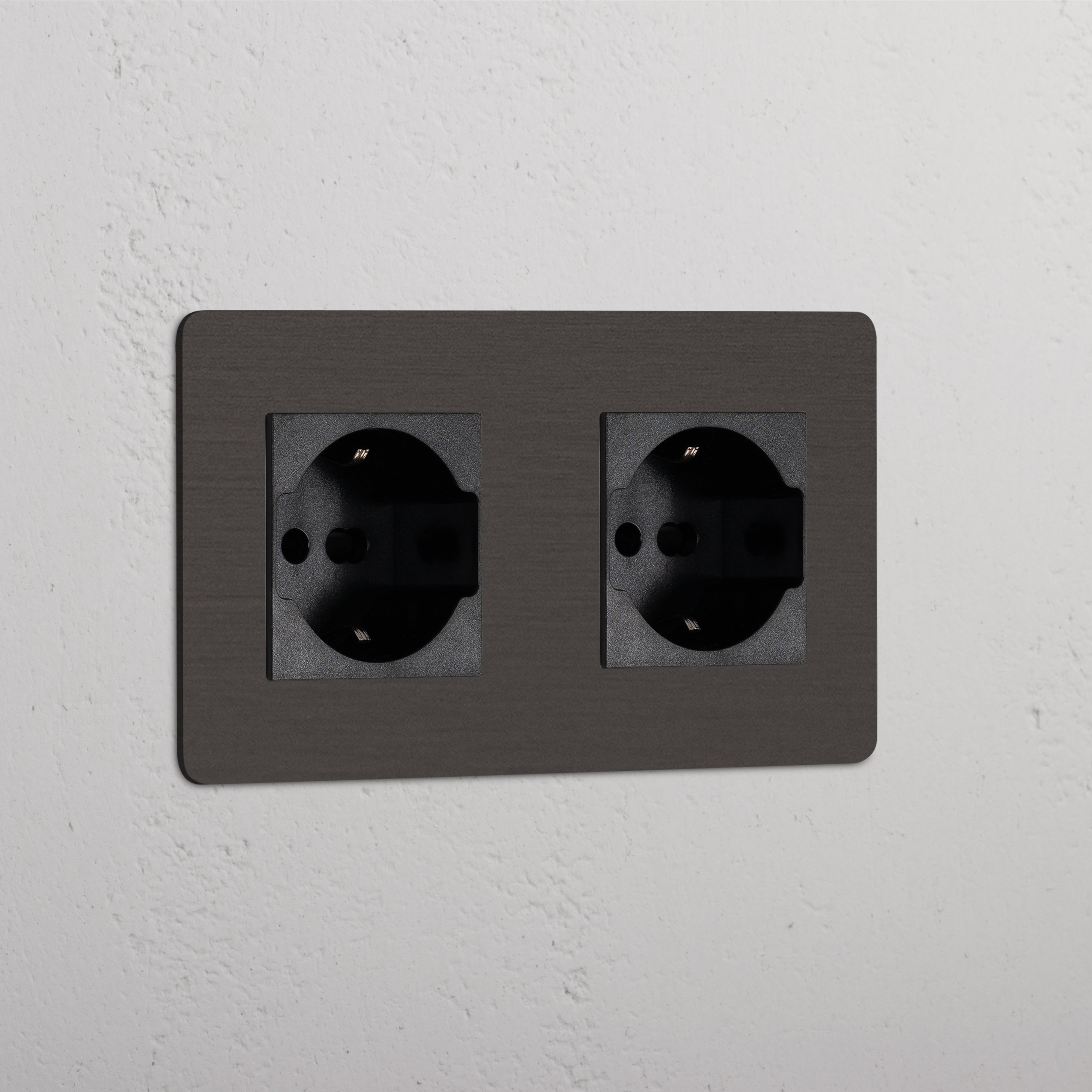 Bronze Black Double 2x Schuko/Bipasso Module wall socket, mounted on a white textured surface.
