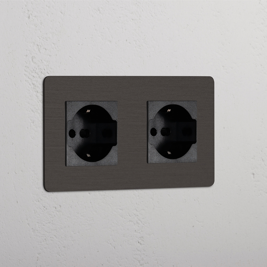 Bronze Black Double 2x Schuko/Bipasso Module wall socket, mounted on a white textured surface.