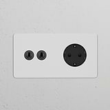 Double 2x Toggle Switch + Schuko Type F Module in paintable bronze black against a textured wall.