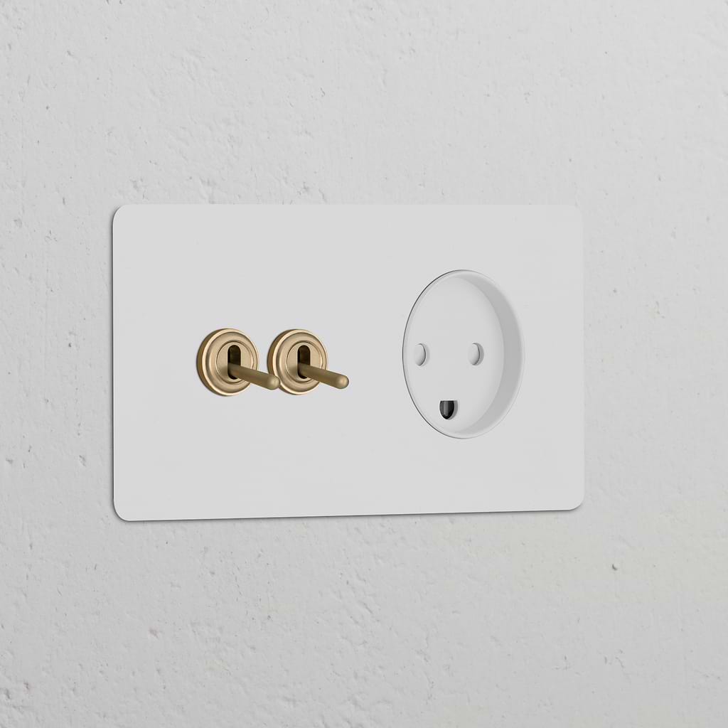 Paintable antique brass double toggle switch and Danish Type K power module on a white wall.